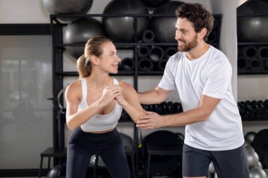 Çapraz eğitim. Spor salonunda antrenörle egzersiz yapan sarışın genç bir kadın.