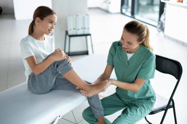 Klinikte bacak esnetme ve iyileşme pratiği sırasında hastaya yardım eden terapist.