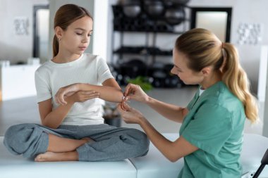 Çocuk bakımı sırasında kolundaki küçük yarayı tedavi eden hemşire.