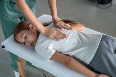 Terapist klinikte fizyoterapi yaparken çocuk sakince yalan söylüyor.