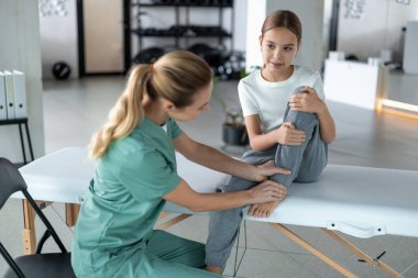 Pediatrik fizyoterapist hastanede çocuğun bacak hareketliliğine odaklanıyor.