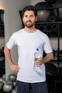 Su dengesi. Spor salonunda elinde bir şişe suyla siyah saçlı, beyaz bir genç.