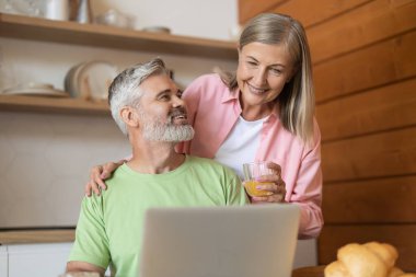 Ev mutfağında teknoloji kullanarak birlikte poz veren mutlu çift.