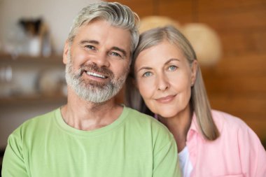 Modern mutfak arka planında yaşlı çift portresi.