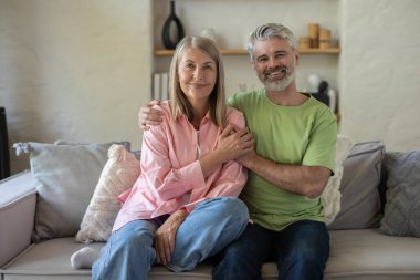 Mutlu çift evde kanepede otururken şefkatli anların tadını çıkarıyorlar.