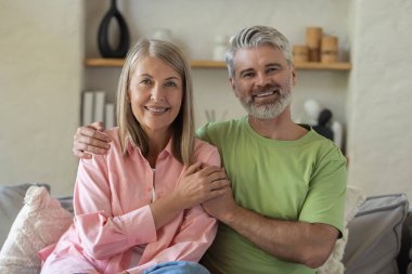 Mutlu çift evde kanepede otururken kucaklaşıp eğleniyor.