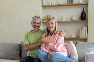 Olgun insanlar kanepede oturur ve kucaklaşır. Oturma odasında aşk anının tadını çıkarırlar.