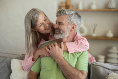 Sevgi dolu bir çift kanepede oturup yakınlığın tadını çıkarıyor. Oturma odasında sıcaklığın tadını çıkarıyorlar.