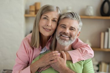 Olgun çift kanepede kucaklaşır rahatlar ve birlikte sakin bir anın tadını çıkarırlar.