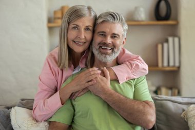 Olgun insanlar kanepede kucaklaşır ve dinlenir. Birlikte sıcacık anın tadını çıkarırlar.