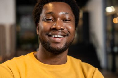 Kameraya bakan kendine güvenen adam modern iç mekanda samimi bir gülümseme ile