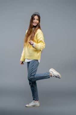 Mutlu ve neşeli. Sarı kazaklı tatlı genç kadın mutlu ve neşeli hissediyor.
