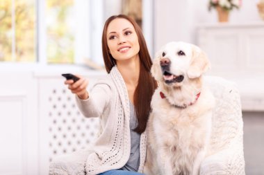 Young girl showing something to her dog on TV.