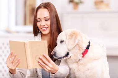 Young lady showing a book to her pet.