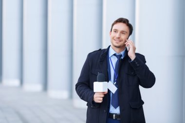 Smiling newsman is speaking on the phone.