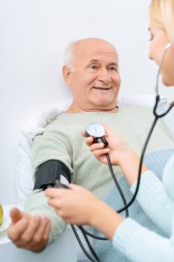 Granddaughter checks blood pressure of her granddad.