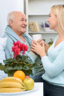 Smiling senior aged man receives a cup of tea.