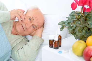 Worried elderly patient is calling somebody.