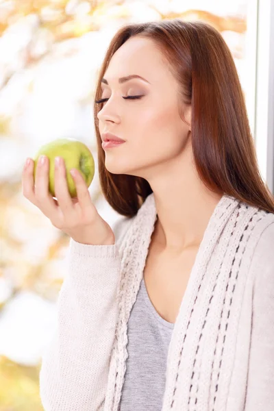 Жінка з закритими очима насолоджується запахом яблука . — стокове фото