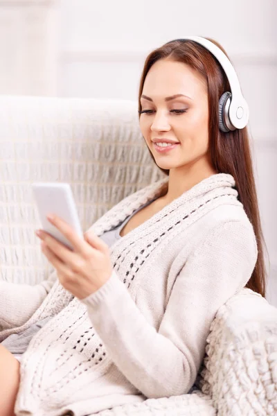 Chica joven en el sillón escuchando música . — Foto de Stock