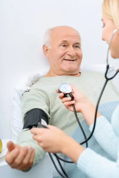 Nieta comprueba la presión arterial de su abuelo . — Foto de Stock