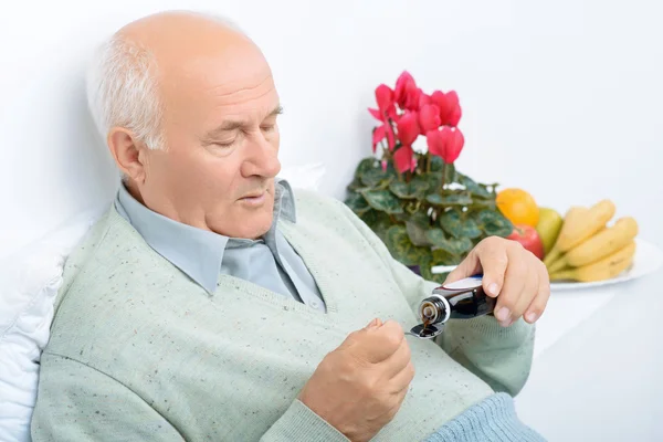 Senior aged man pours himself cough syrup. — Stock Photo, Image