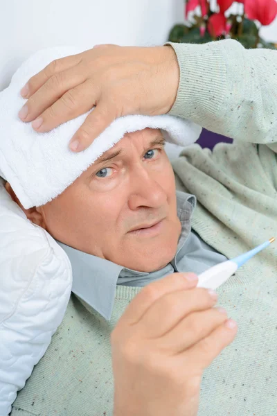 Gentleman uses wet towel while holding the thermometer. — ストック写真