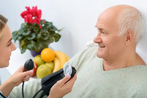 Young granddaughter uses stethoscope to check blood pressure. — Stock Photo, Image