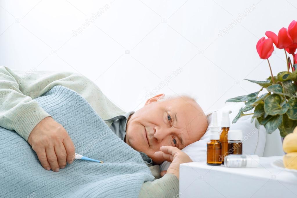 Senior aged man is resting while holding a thermometer.
