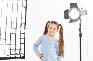 Small girl smiles charmingly during shooting process. clipart
