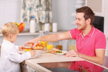 Father and son are having breakfast.