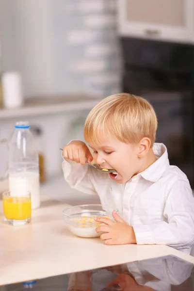 Menino pequeno come flocos de milho com muito apetite . — Fotografia de Stock