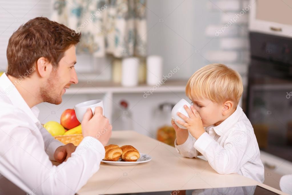 Father and son are drinking morning beverages.