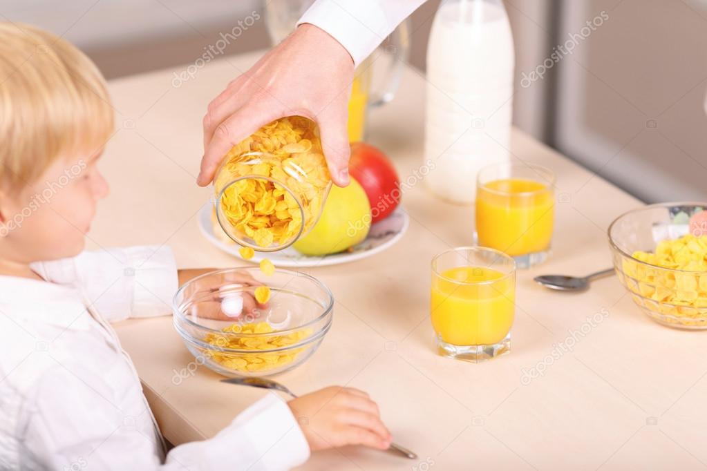 Dad offers cornflakes to his kid.
