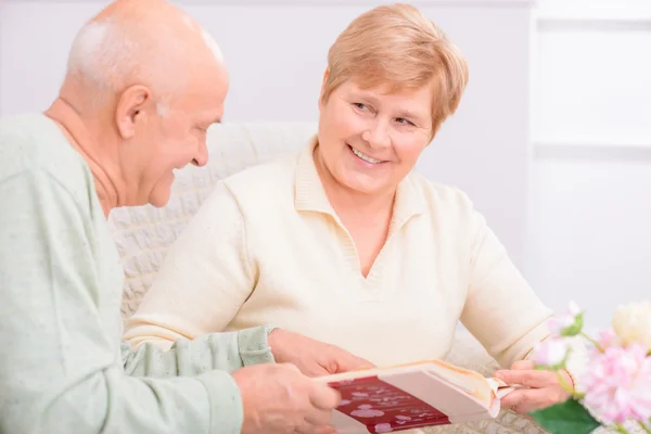 Pleasant couple looking through photo album — Stock Photo, Image