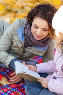 Anne ve kızı kitap okuyor.