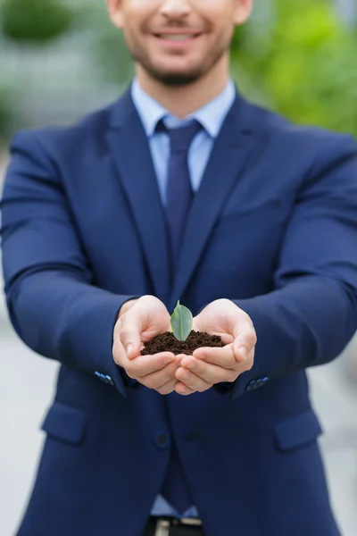 Agréable homme d'affaires tenant le terrain dans les mains — Photo