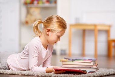 girl is lying on the floor and reading.