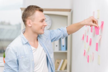 Workman attaching post-it notes to the wall.