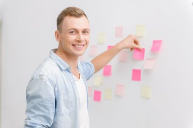 Smiling employee is busy with post-it notes.