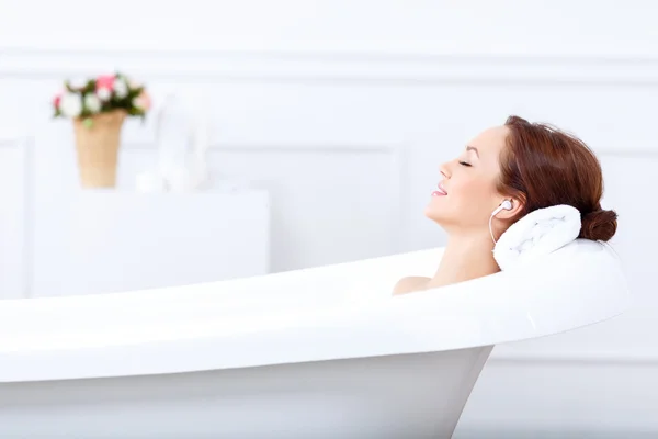 Chica escuchando música mientras toma un baño — Foto de Stock