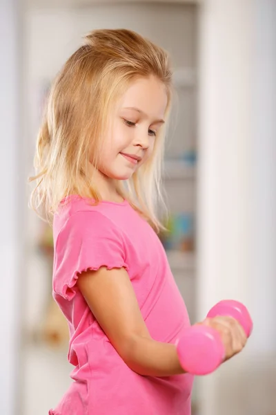 Pieni tyttö nostamassa käsipainoa . — kuvapankkivalokuva