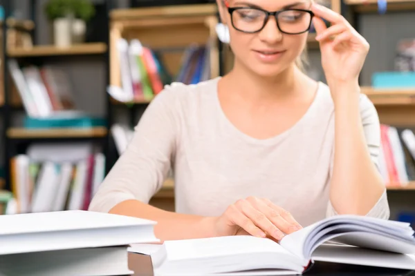 Menina usa óculos para ler um livro . — Fotografia de Stock