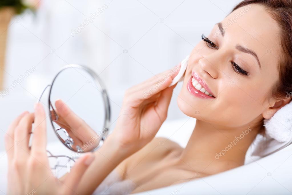 girl looking in the mirror while taking  a bath