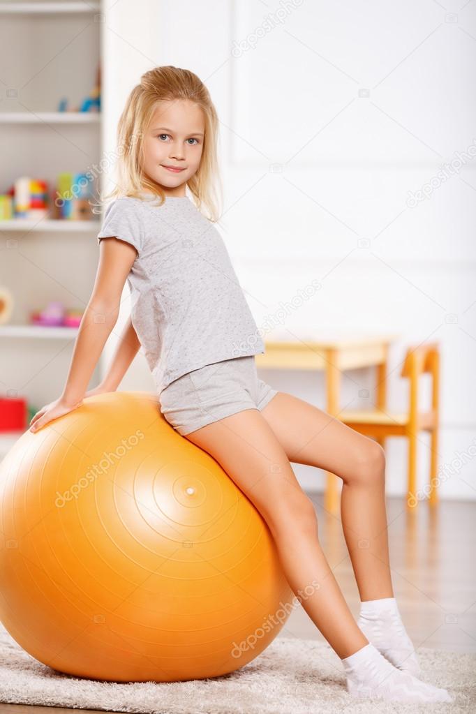 Little girl leaning against a gym ball.