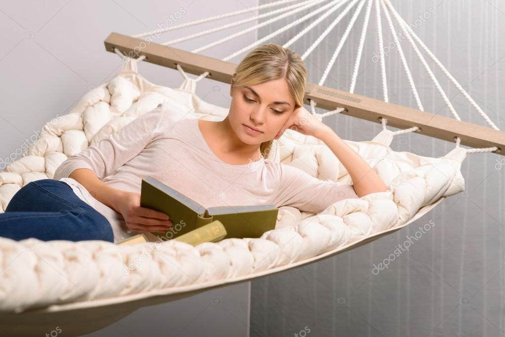 Young girl is reading  in the hammock.