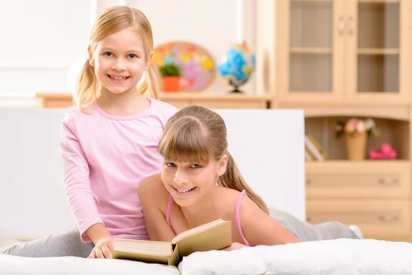 Cheerful sisters reading book — Stok fotoğraf
