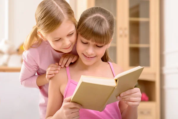 Cheerful sisters reading book — Stok fotoğraf