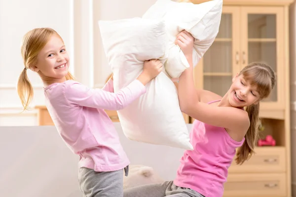 Irmãzinhas simpáticas lutando com travesseiros — Fotografia de Stock