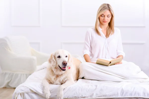 Mulher carinhosa deitada na cama com seu cão — Fotografia de Stock